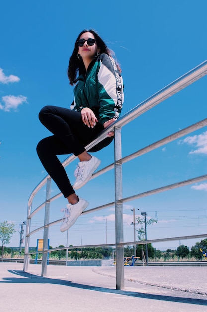 青い空に逆らってレールに座っている女性の低角度の景色