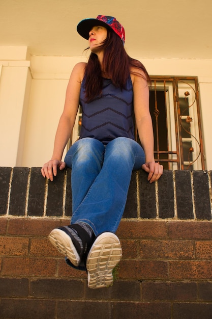 Photo low angle view of woman sitting on retaining wall