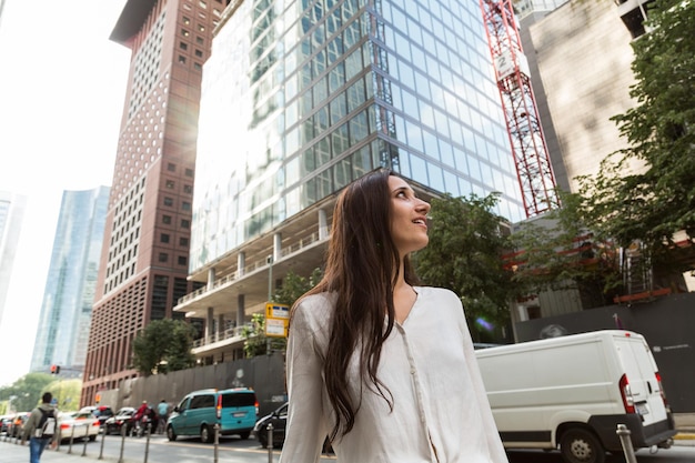 Photo low angle view of woman smiling while standing against buildings in city