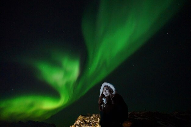 Foto vista ad angolo basso di una donna in piedi contro l'aurora boreale di notte