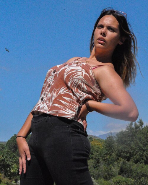 Low angle view of woman standing against blue sky