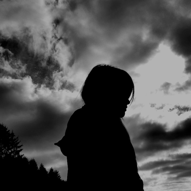 Photo low angle view of woman standing against cloudy sky