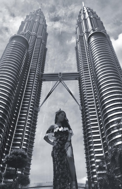 Foto vista a bassa angolazione di una donna in piedi vicino alle torri di petronas