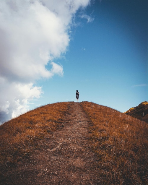 Photo low angle view of woman standing on hill against sky