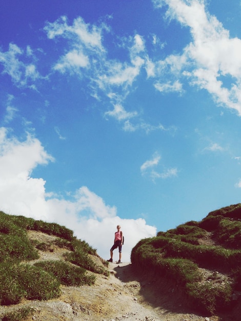 Photo low angle view of woman standing on mountains against cloudy sky