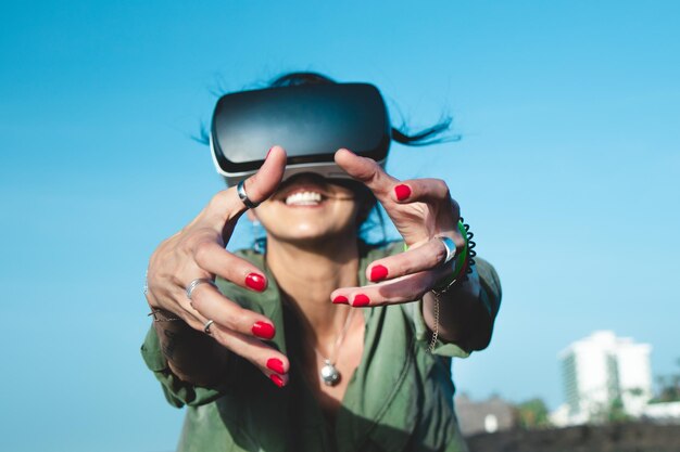 Low angle view of woman using virtual reality simulator against sky