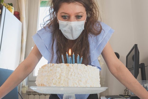 Photo low angle view of woman wearing mask looking at birthday cake on table
