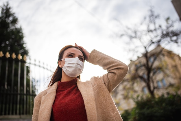 空に向かって立っているマスクをかぶった女性の低角度の景色