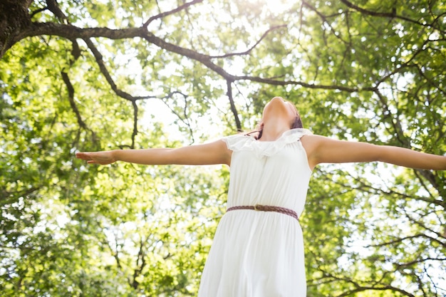 Low angle view of woman in white dress against trees