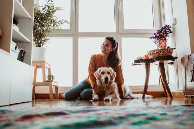 Photo low angle view of woman with dog sitting on floor at home