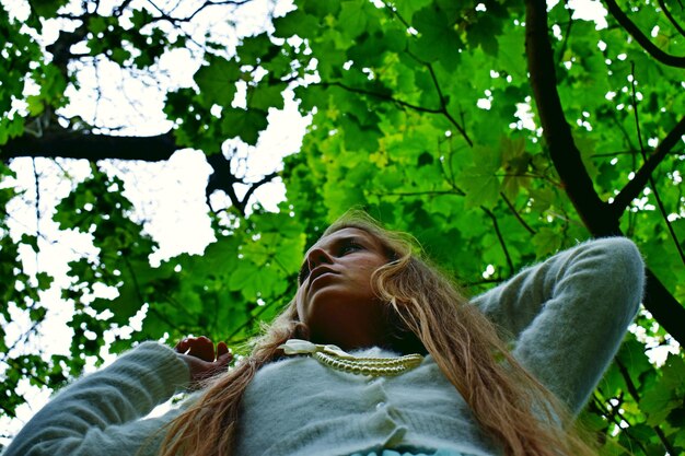 Foto vista ad angolo basso di una donna con i capelli lunghi contro gli alberi
