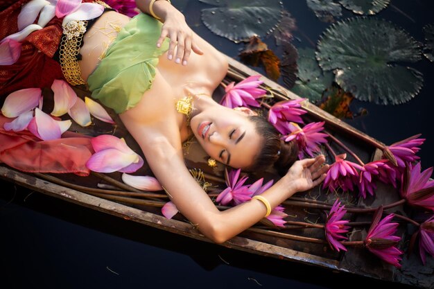 Foto vista ad angolo basso di una donna con petali rosa che galleggia sull'acqua