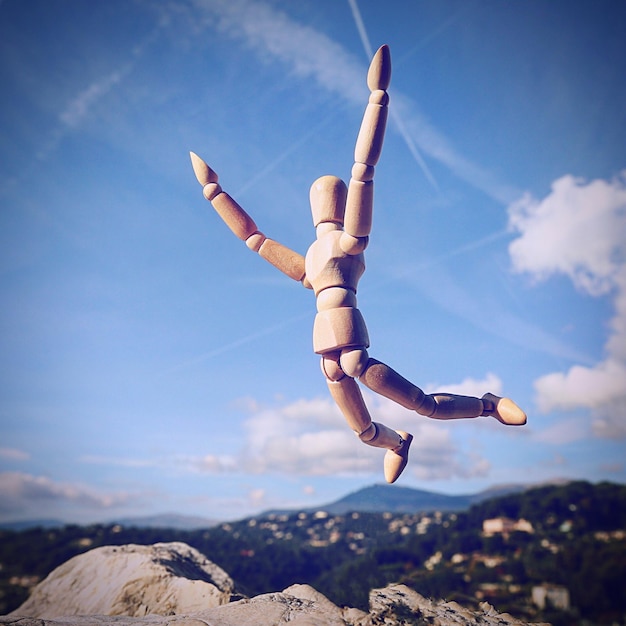 Photo low angle view of wooden mannequin against blue sky