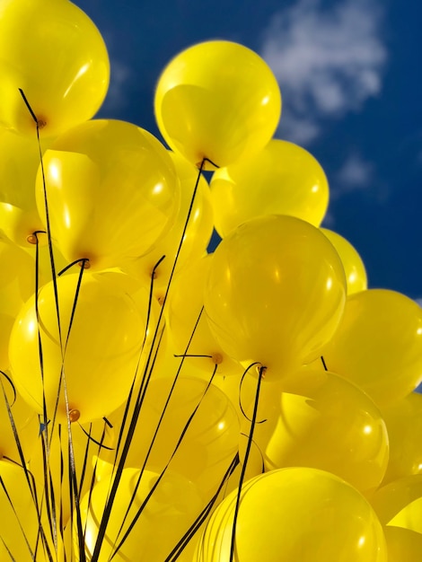 Low angle view of yellow balloons against sky