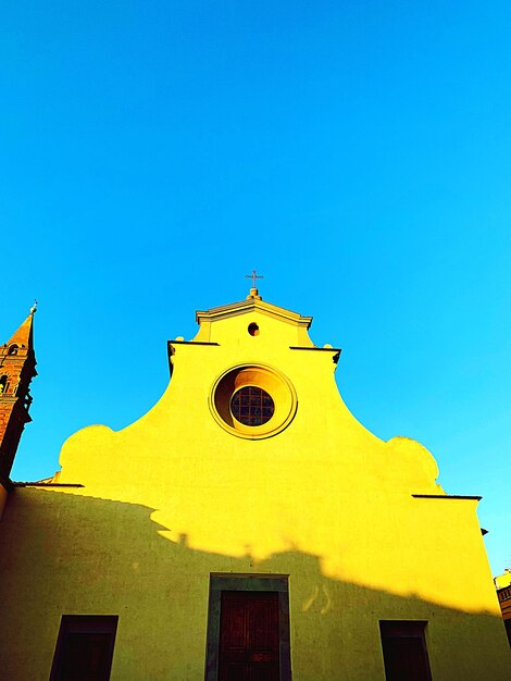 Low angle view of yellow building against clear blue sky