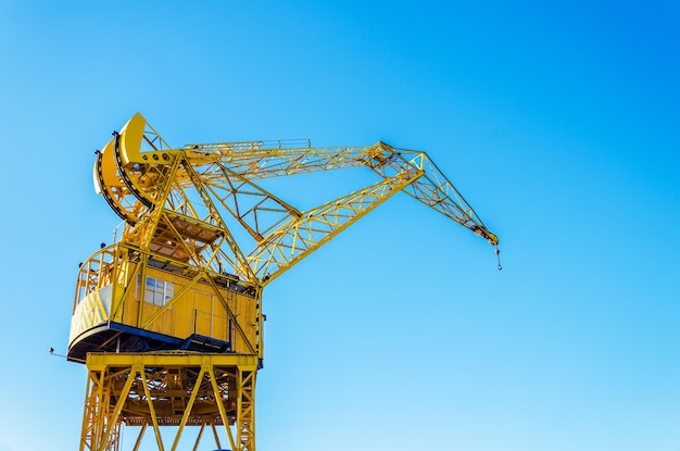 Low angle view of yellow crane against clear blue sky on sunny day