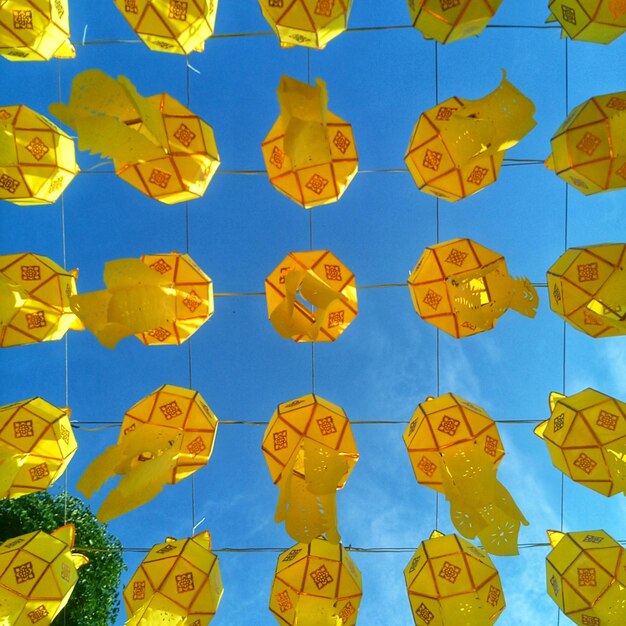 Photo low angle view of yellow lanterns hanging against sky