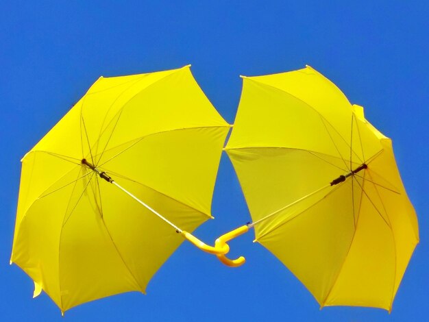 Low angle view of yellow umbrella against clear blue sky