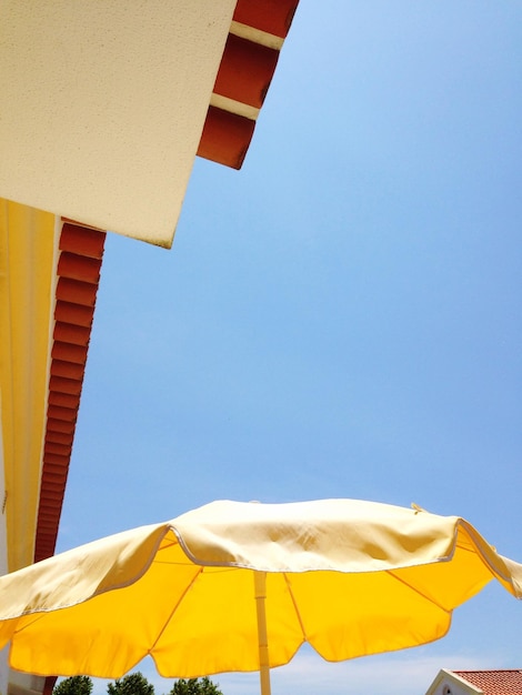 Foto vista a basso angolo dell'ombrello giallo e dell'edificio contro un cielo limpido