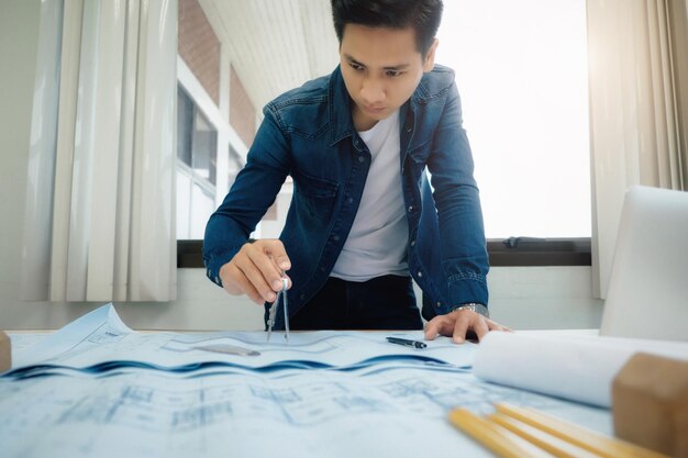 Low angle view of young male architect working at desk in office