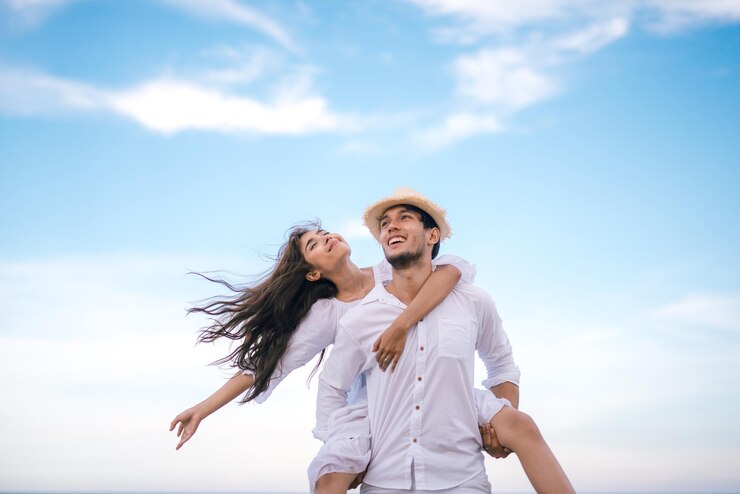 Photo 空に向かってガールフレンドに背中を背負わせている若者の低角度の写真