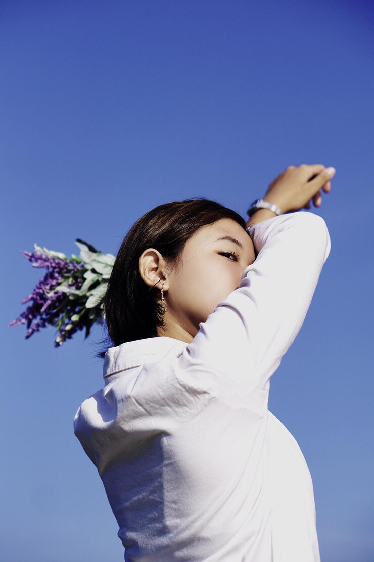 Photo 一位年輕女子站在清<unk>的藍天下,低角度觀看
