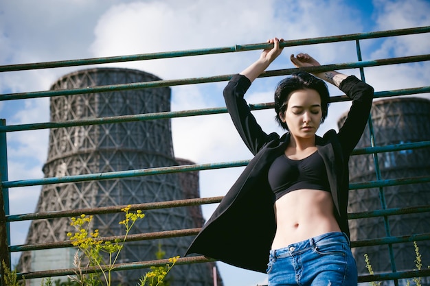 Photo low angle view of young woman standing by fence against silo