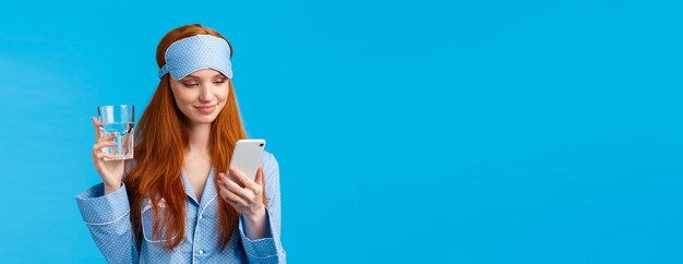 Low angle view of young woman wearing hat against blue background