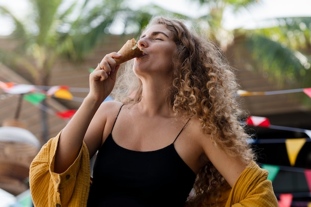 Donna di angolo basso che mangia il cono gelato