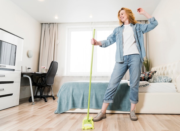 Low angle of woman having fun while mopping the floor