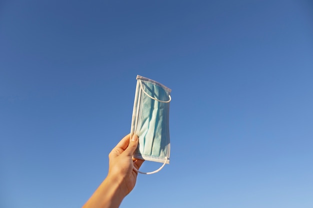 Photo low angle woman holding face mask