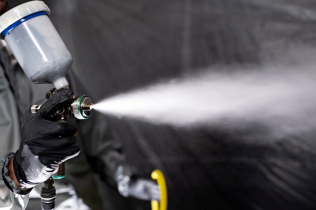 Low angle worker spraying powder paint
