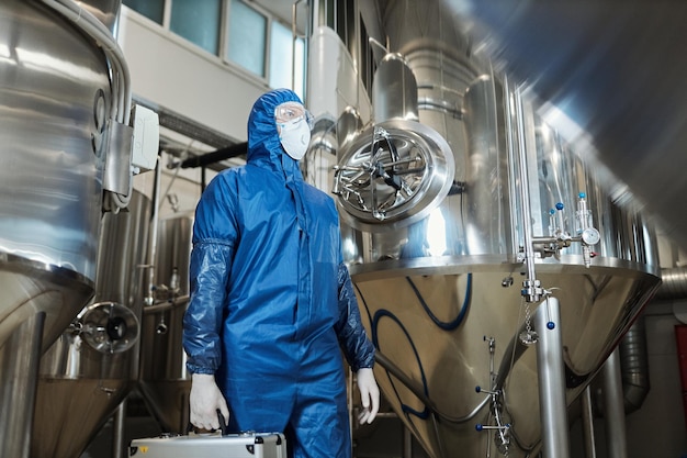 Low angle worker wearing protective gear in chemical factory workshop