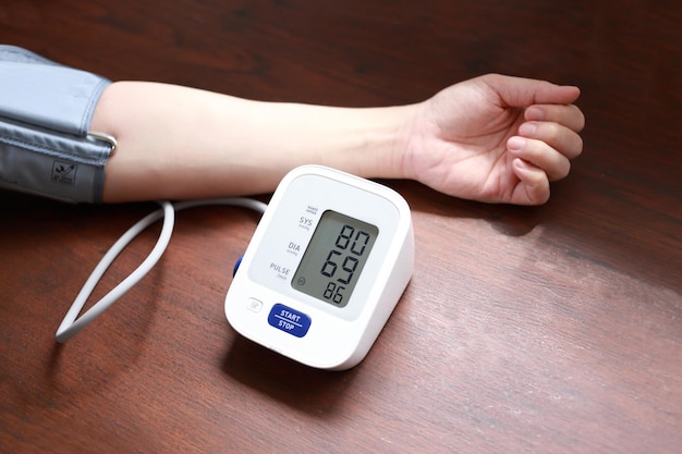 Photo low blood pressure hand wear blood pressure arm cuff on wooden desk