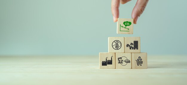 Low carbon emission and net zero concept Climate changing problems solving goals Stacking wooden cubes with decarbonization icon on pollution causes icons on grey backgroundcopy space LCA