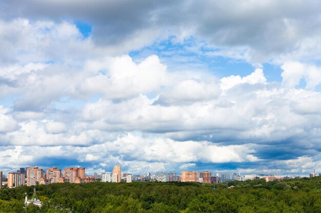 Низкие плотные белые облака в голубом небе над городом