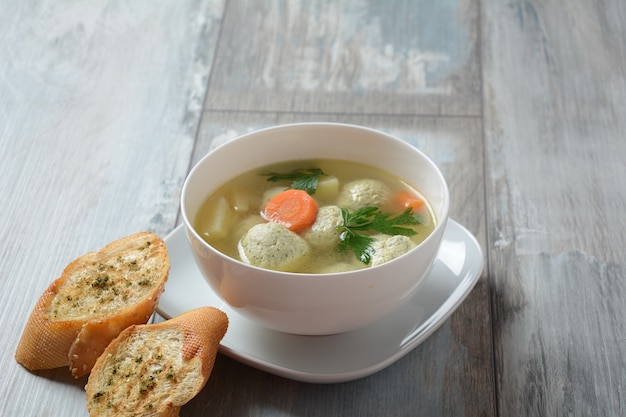 Low fat vegetable soup with chicken meatballs potato and carrot and fresh herbs in bowl