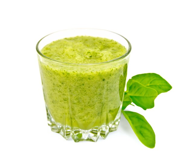 Low glass cup with a cocktail of spinach, spinach leaves isolated on white background