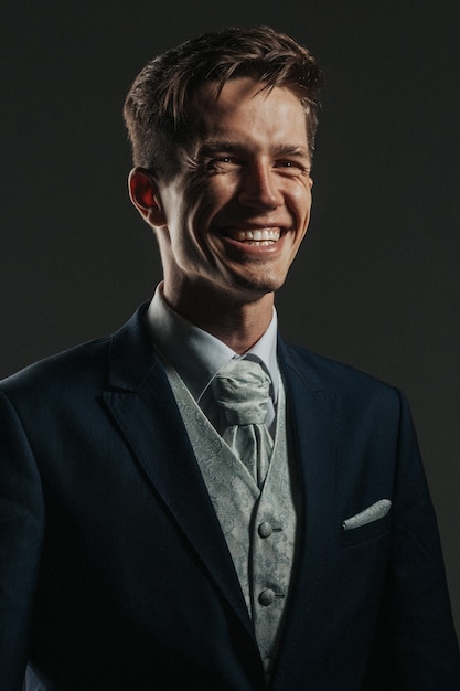 Ritratto in studio low-key di bell'uomo d'affari con un sorriso fantastico vestito con un abito a tre pezzi.