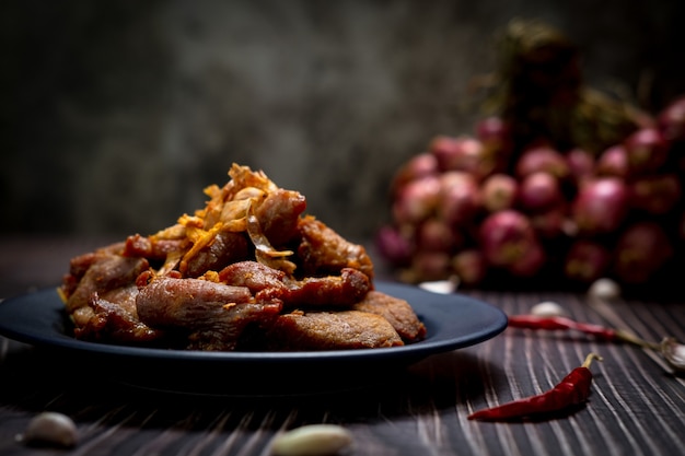 Foto fotografie con scarsa illuminazione di maiale fritto con aglio pronto per essere servito