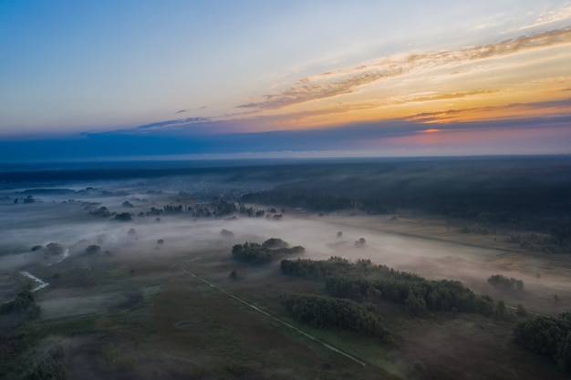 Low morning fog in the meadow at dawn. Natural landscape from aerial view.