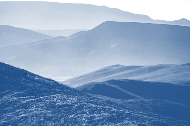 Low mountains in mist colored in trendy Classic Blue pantone color of the year 2020