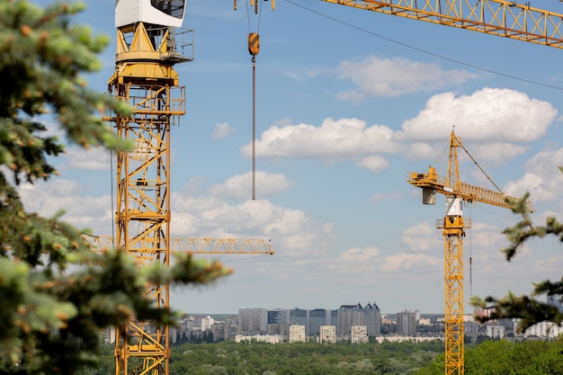 Concetto di edificio basso: gru a torre per la costruzione di una casa a schiera in un'area del parco