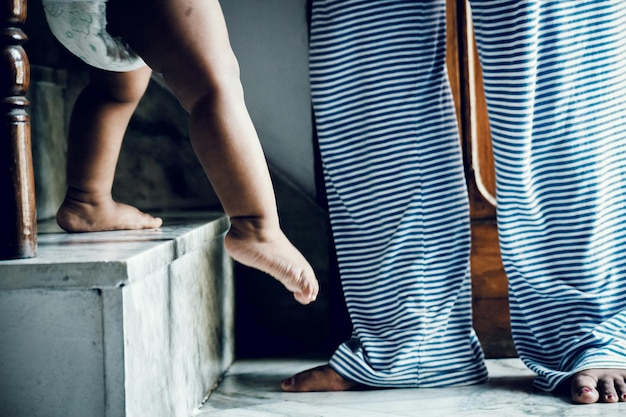 Foto sezione bassa della bambina che scende le scale mentre la madre è a casa