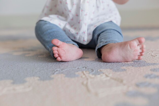 Photo low section of baby girl sitting on mat