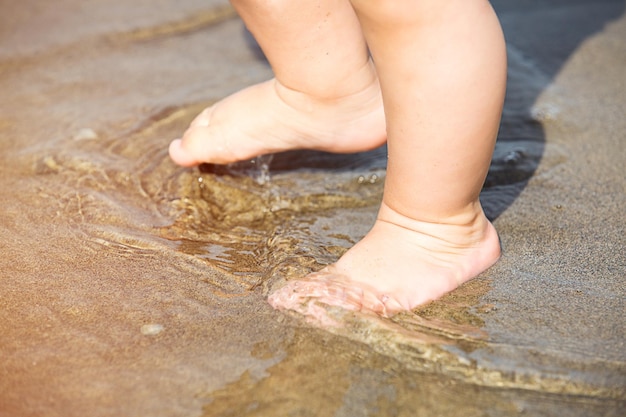 Photo low section of baby standing on shore at beach