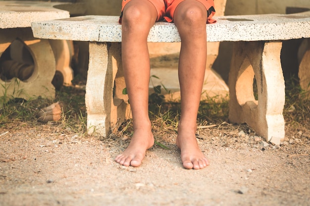 Photo low section of boy sitting on bench