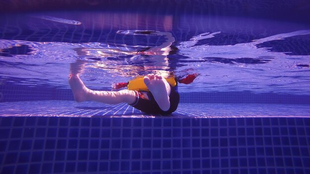 Foto sezione bassa di un ragazzo che nuota in piscina