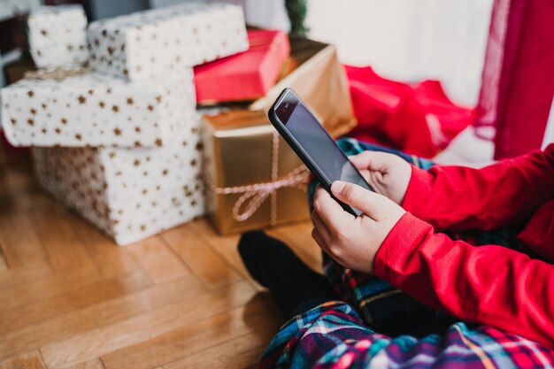 Photo low section of boy using phone while sitting on floor at home