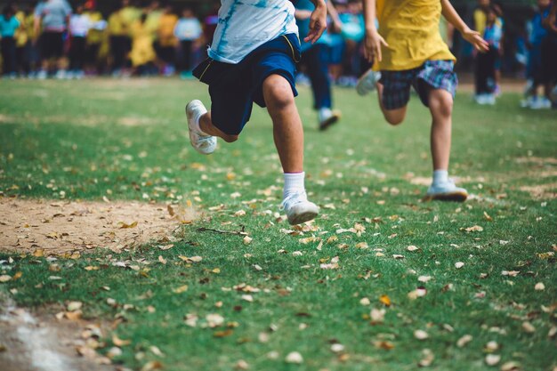 Photo low section of boys running on grassy field